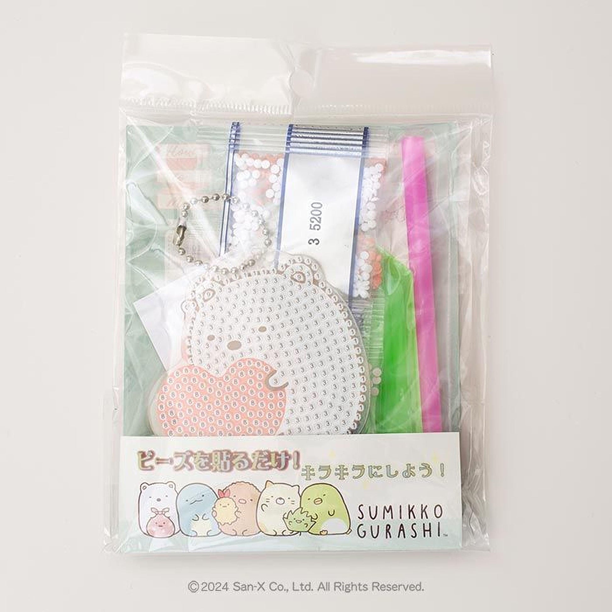 a package with a clear plastic bag, which appears to be a gift or a product. The package contains various items, including a keychain, a pen, and a toothbrush. The packaging also features a label with Japanese text and a cartoon character.