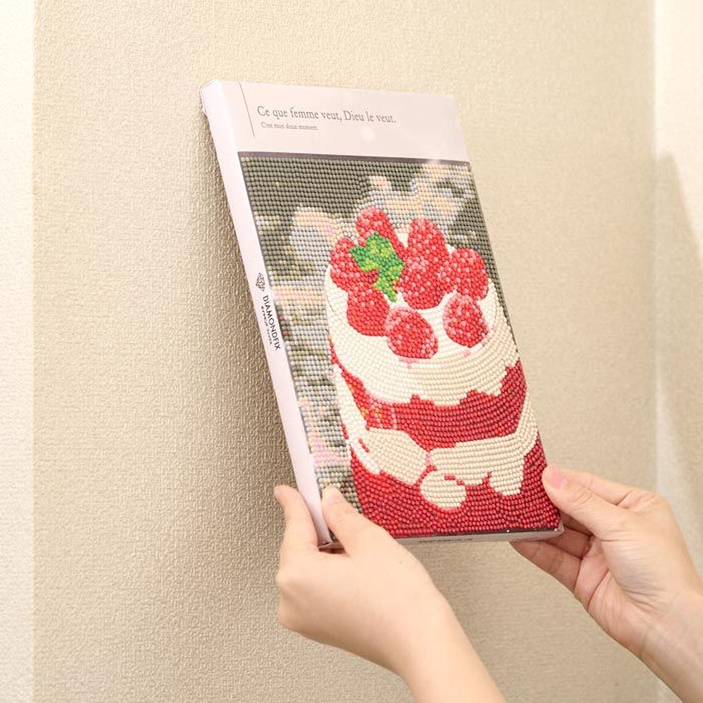 A person is holding a book with a cover featuring a cake decorated with red berries.