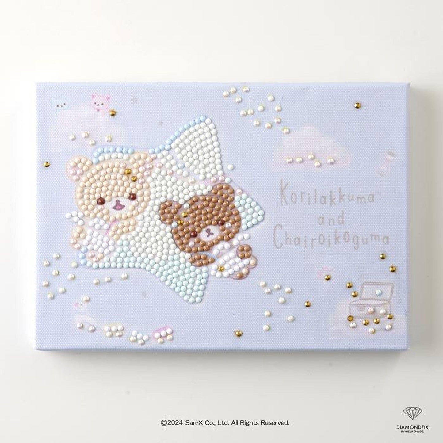 The image is a canvas featuring two teddy bears, one brown and one beige, lying on a star-shaped background. The background is decorated with small white and gold beads, and the text "Koriakuma" and "Chairoikoguma" is written in the image.