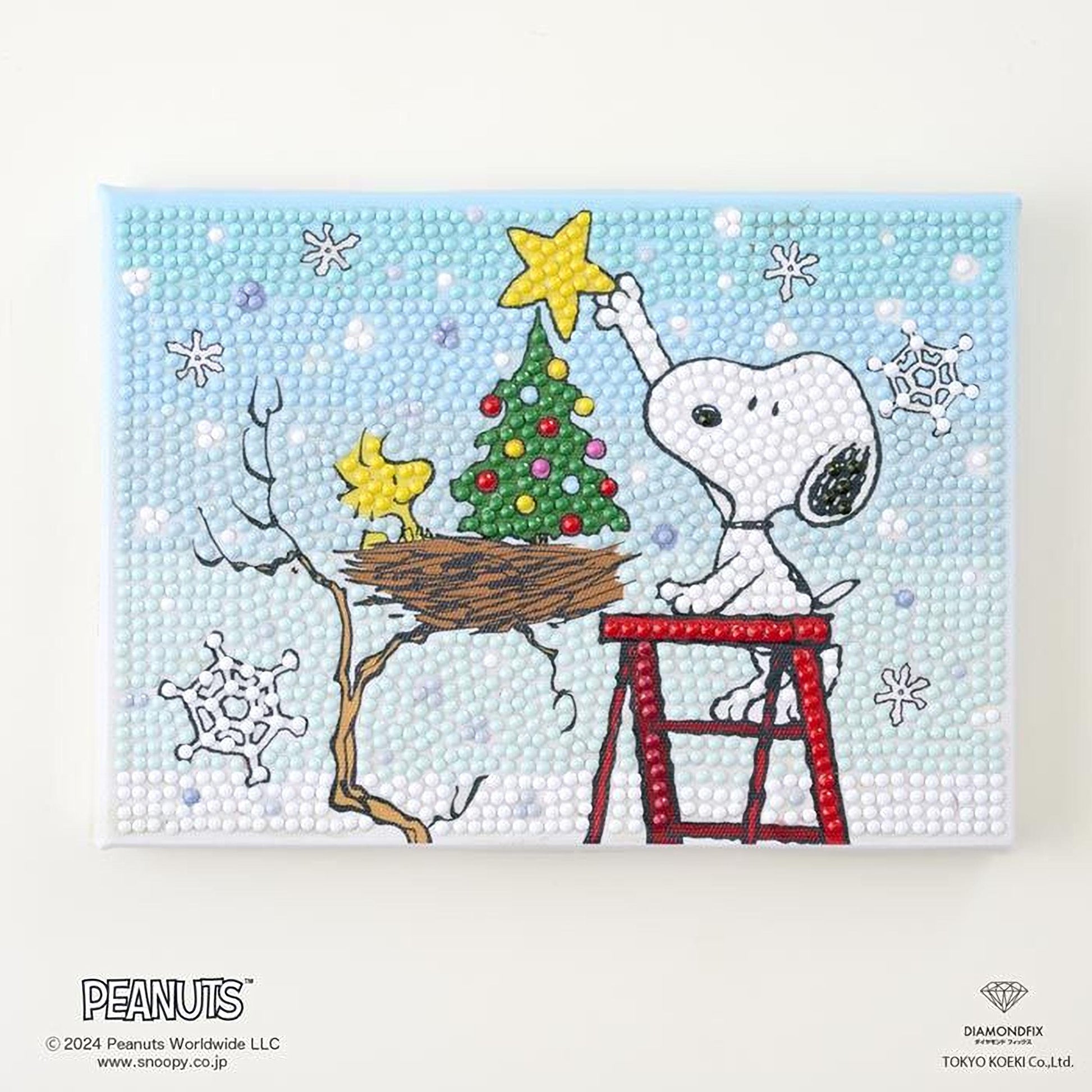 A Peanuts-themed painting depicting Snoopy placing a star on a Christmas tree, with a bird's nest nearby.