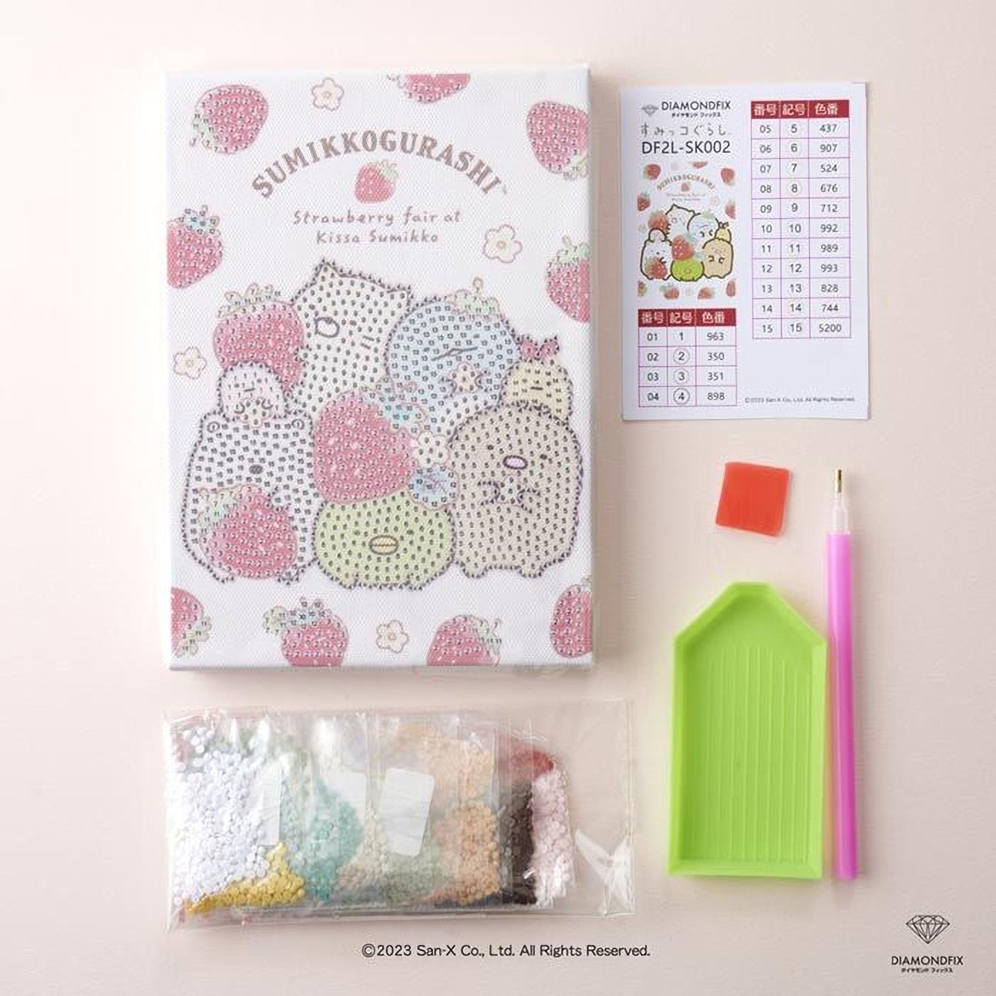 a book, a pen, a diamond tool, and some rice grains, all arranged on a pink background.