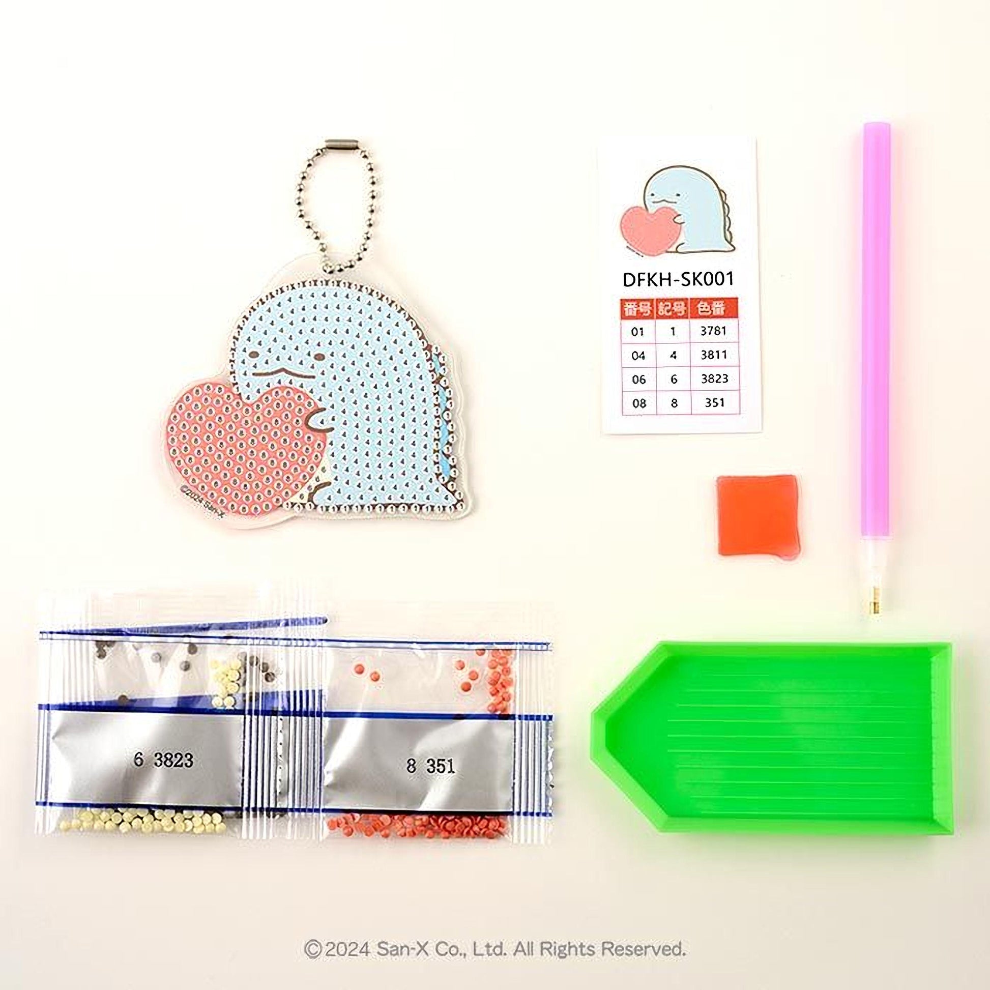 various craft supplies, including a keychain, a price list, a pen, a bag of beads, and a diamond tool.