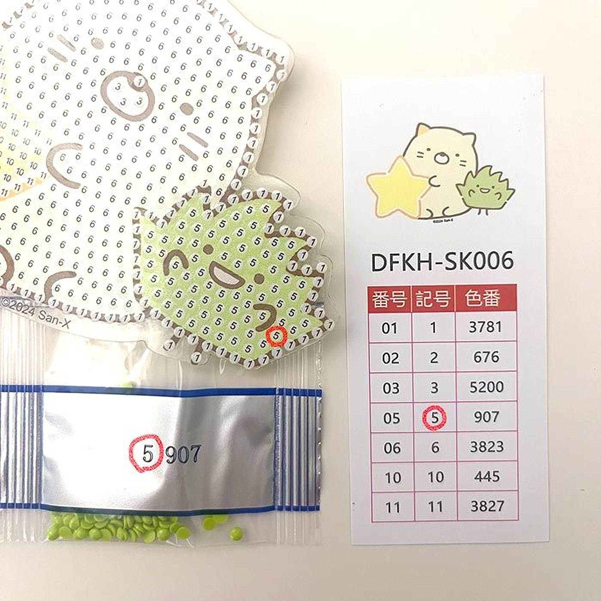 a collection of items, including a sticker with a cartoon cat, a price list, and a bag of green beads.