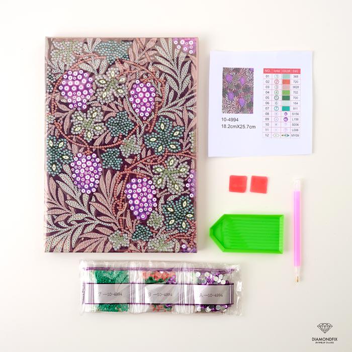 various craft supplies, including a notebook with a floral pattern, a diamond-patterned pen, a set of beads, and a diamond-patterned pen.