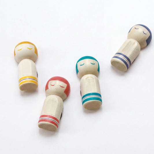 four wooden dolls with colorful hair and eyes, arranged on a white background.