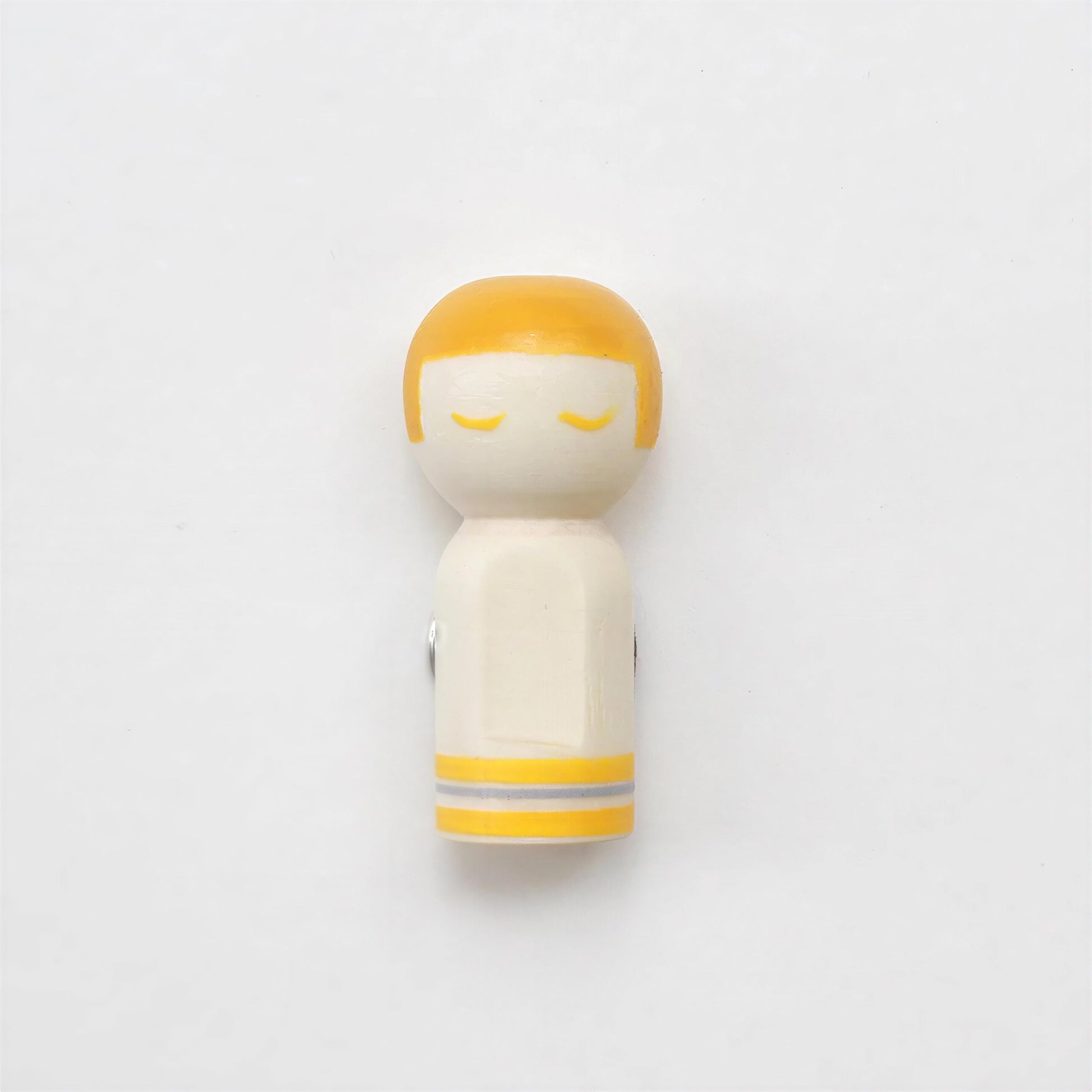 A small wooden figurine with a yellow head and arms, set against a plain white background.