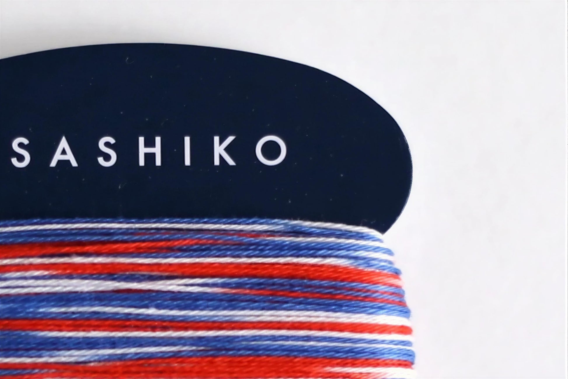 A close-up view of a spool of thread with the word "SASHIKO" printed on it in white text.