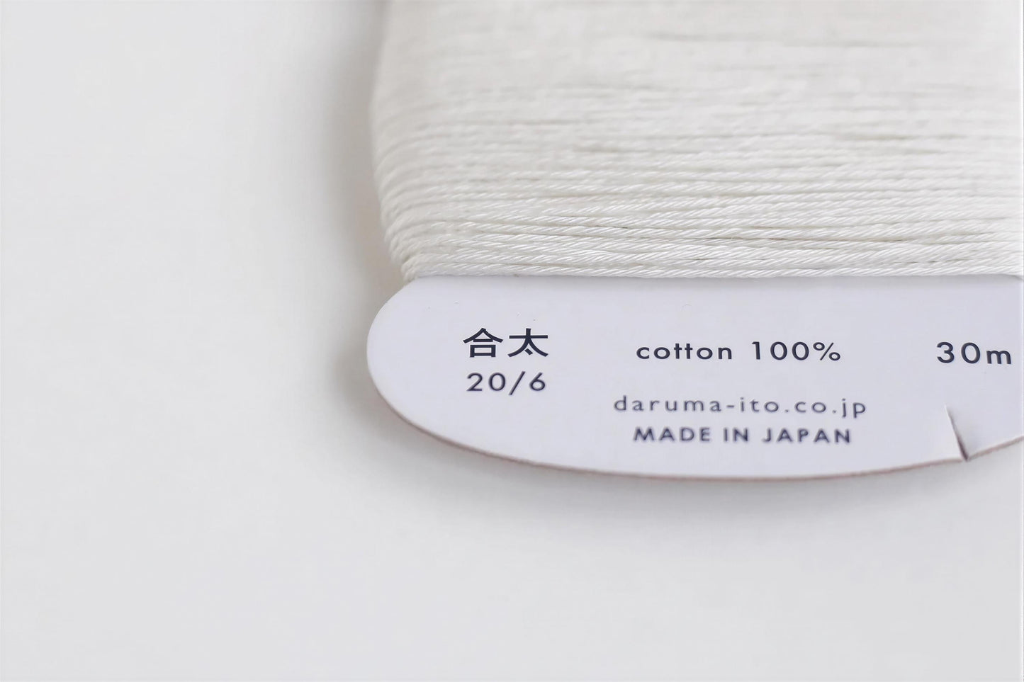 a close-up view of a spool of white thread with text and numbers printed on it.