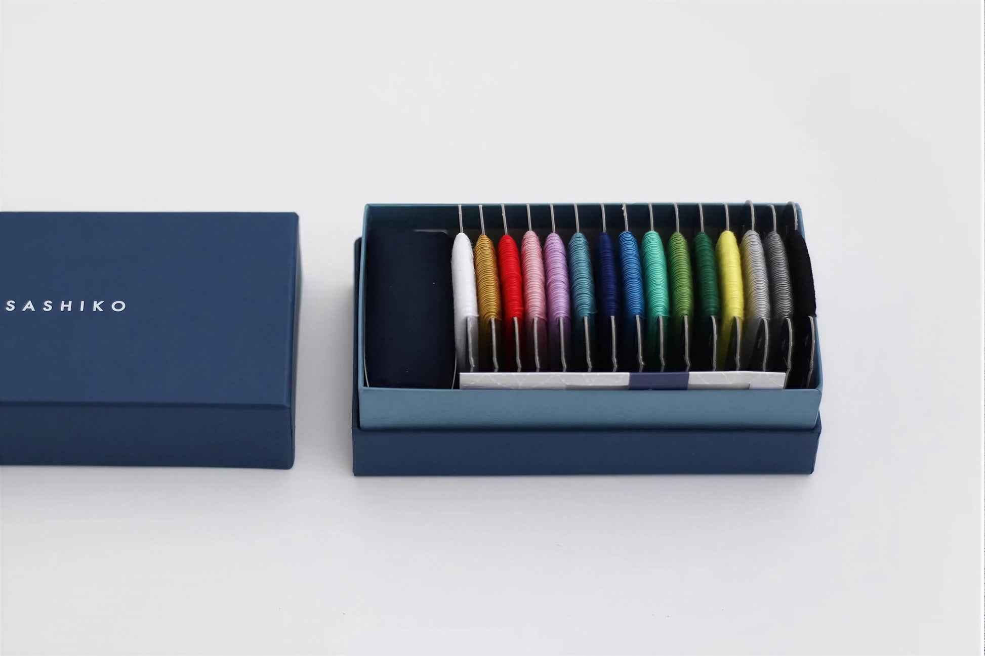 A blue box containing a collection of colorful spools of thread, with the brand name "SASHIKO" visible on the box.
