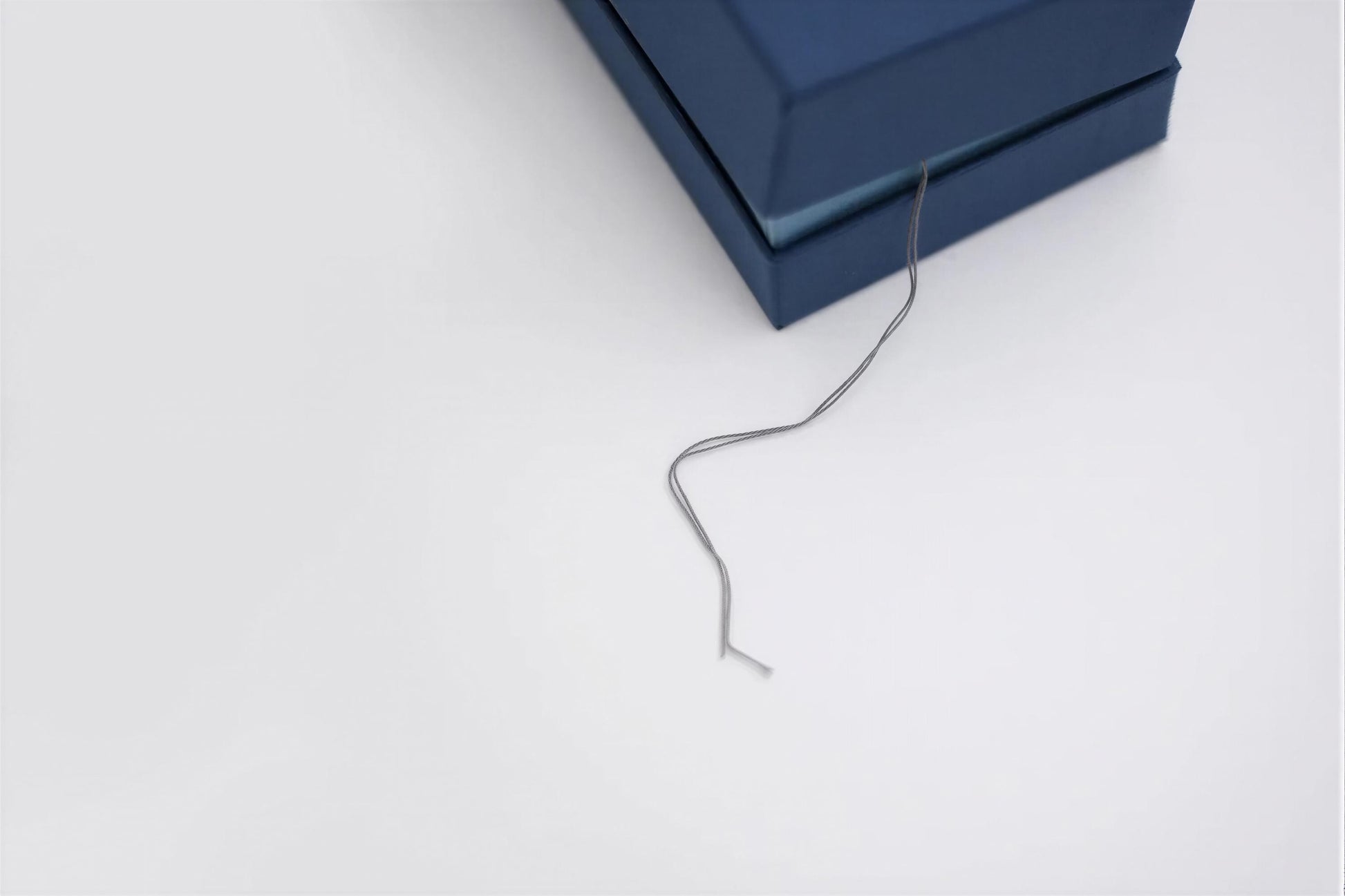 A blue box with a string or cord attached to it, resting on a white surface.