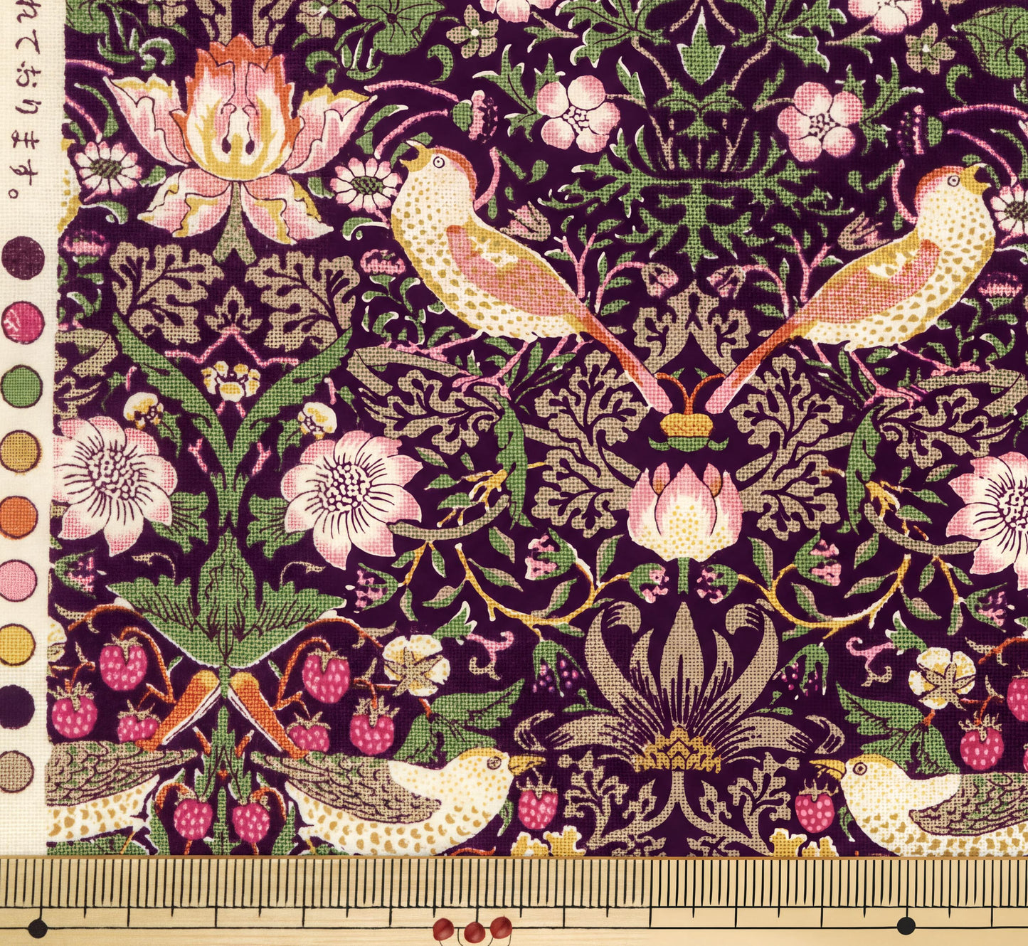 The image is a detailed and intricate fabric pattern featuring a variety of birds, flowers, and berries in shades of pink, green, and purple. The pattern is rich in detail and complexity, showcasing the craftsmanship and artistry of the design.