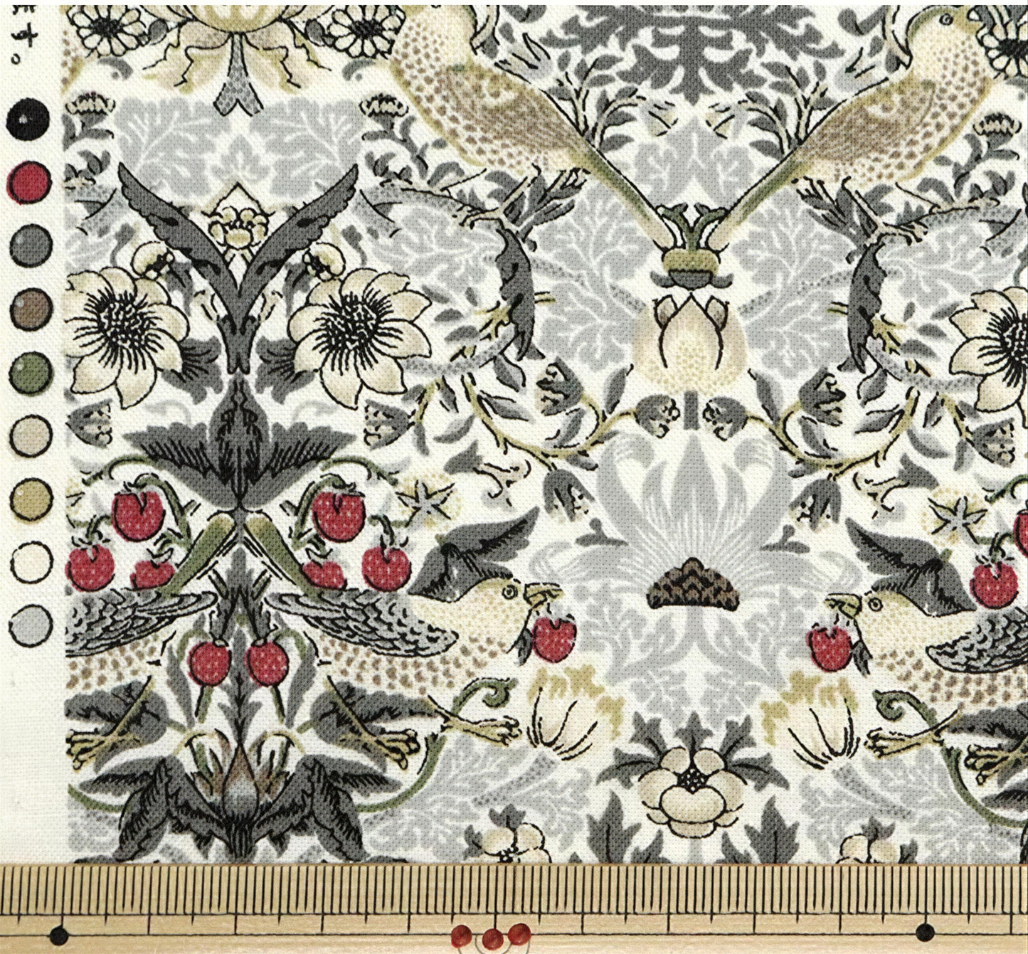 The image is a close-up of a fabric with a repeating pattern of birds, flowers, and berries. The pattern is intricate and detailed, featuring various shades of gray, white, and black. The fabric appears to be a piece of textile, possibly used for clothing or home decor.