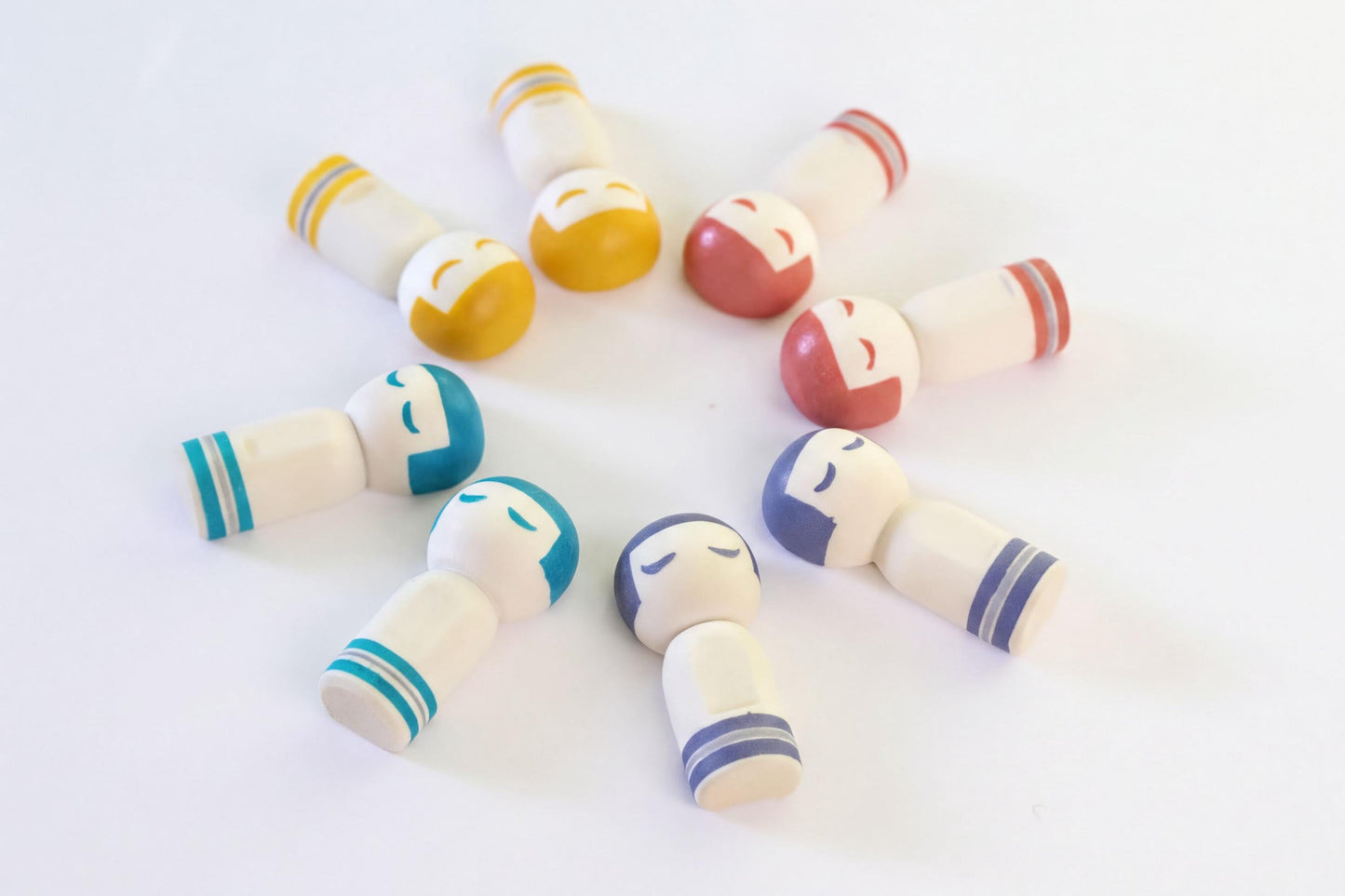A group of colorful wooden dolls arranged in a circular pattern on a white background.