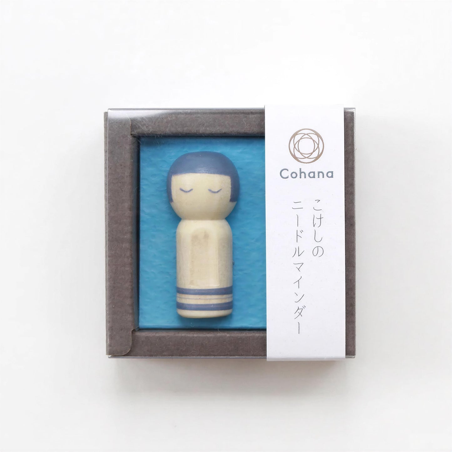 A small wooden doll with blue hair is displayed in a square frame against a blue background.