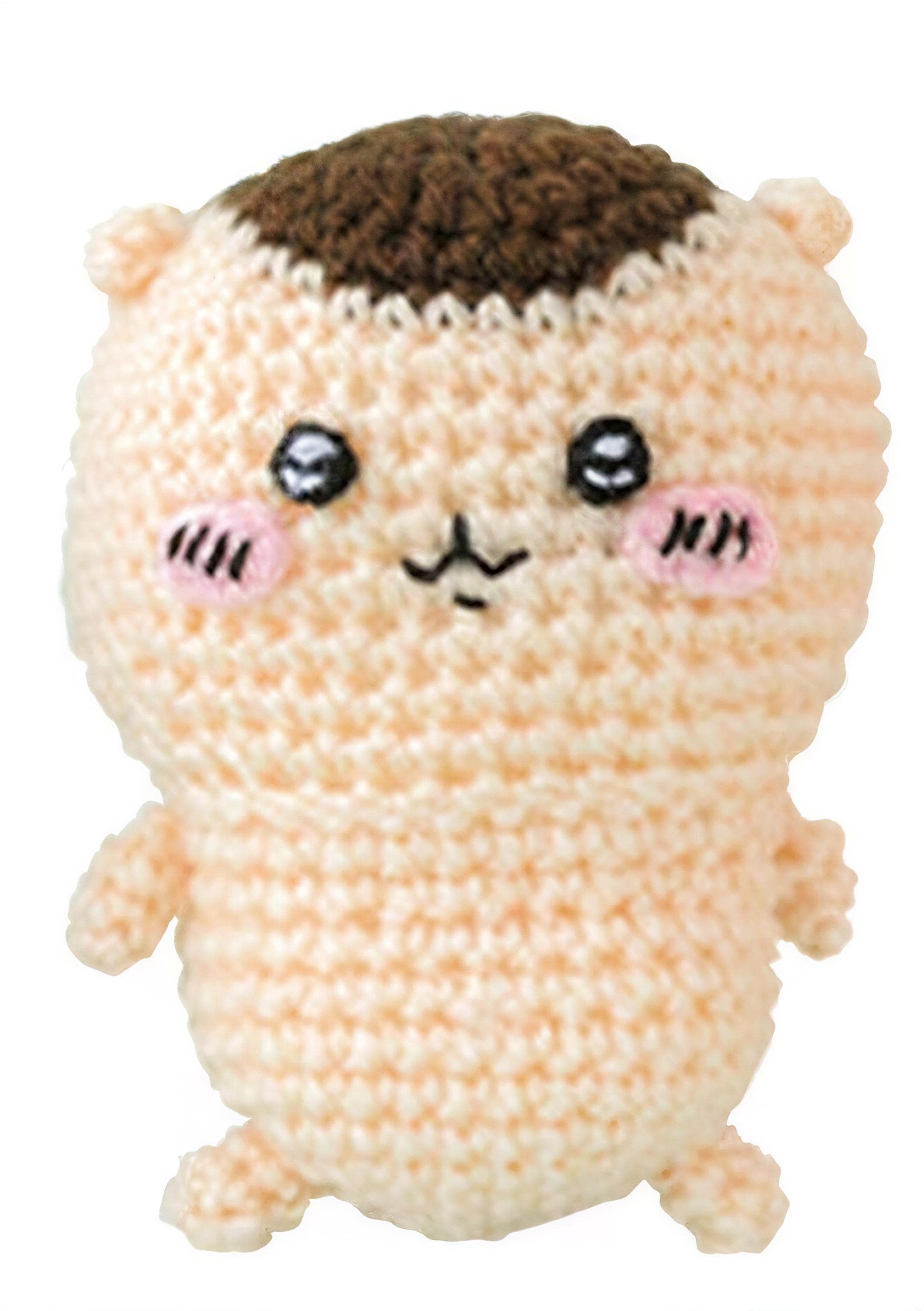 A crocheted doll with a cute face and pink cheeks, featuring a brown top hat.