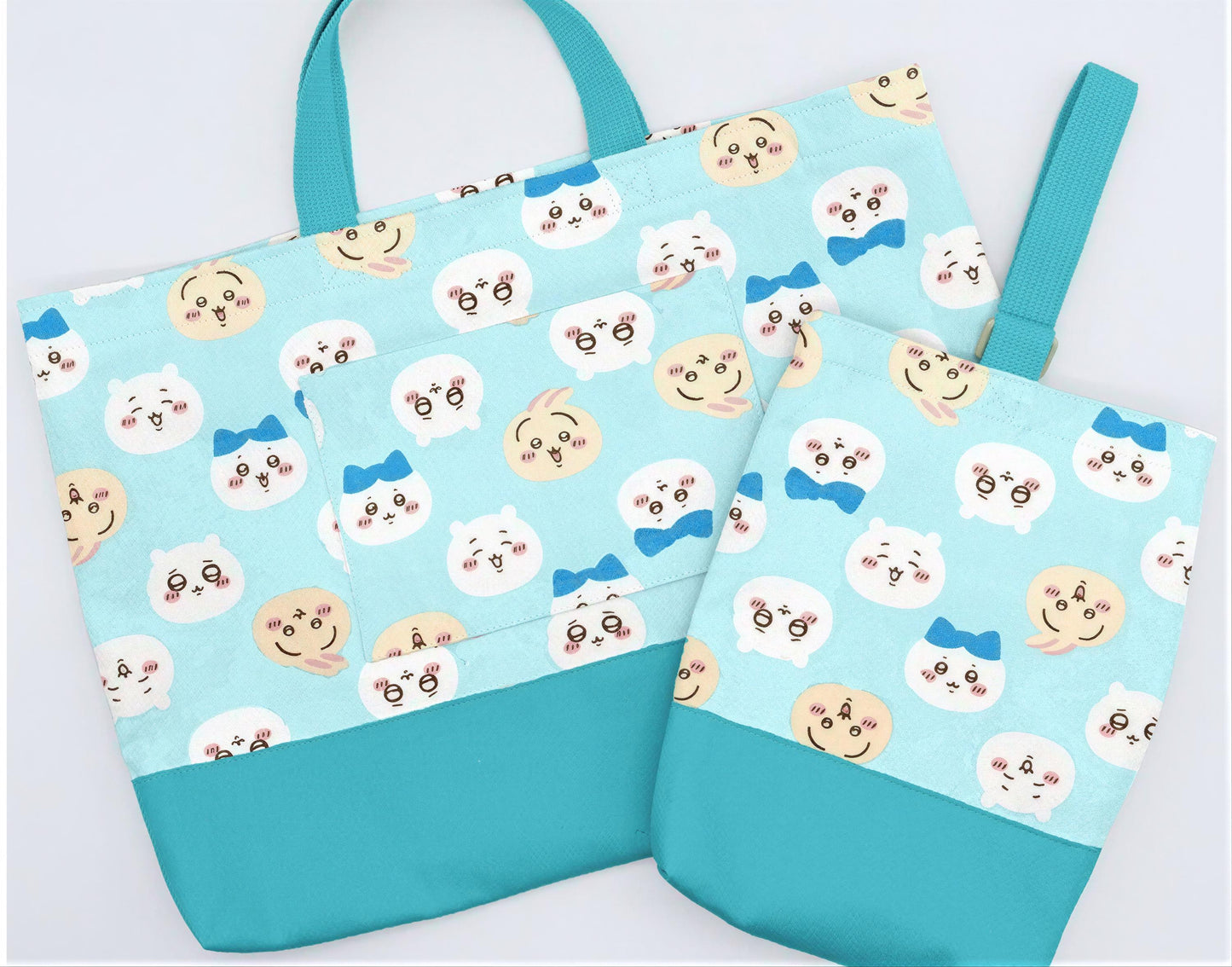 A blue tote bag with a pattern of cartoon cat faces and a matching blue handle.