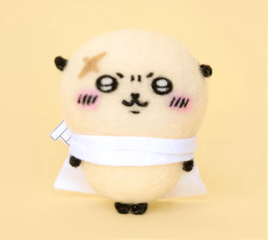 A cute, hand-made plush toy with a round body, large eyes, and a small nose, wearing a white scarf and standing on a yellow background.