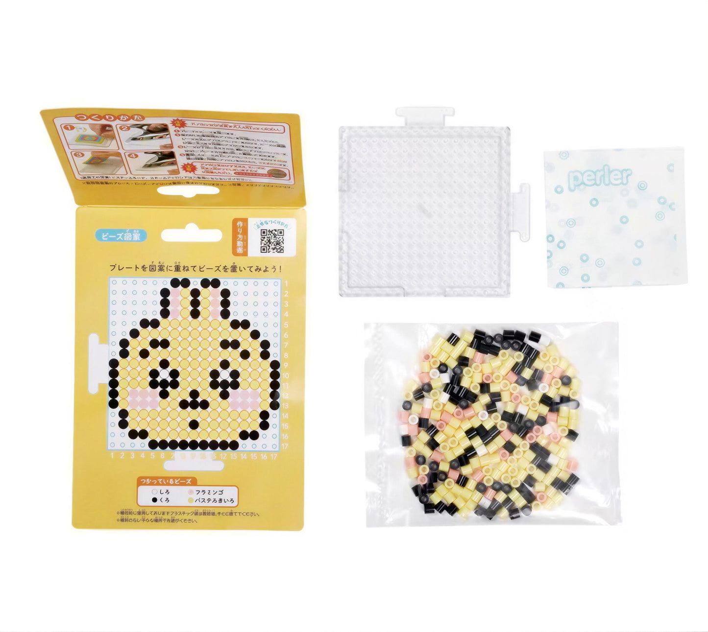 a yellow box with instructions for creating a pixel art design, a clear plastic container filled with small black and white pieces, and a white plastic bag containing additional pieces.