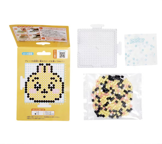 a yellow box with instructions for creating a pixel art design, a clear plastic container filled with small black and white pieces, and a white plastic bag containing additional pieces.