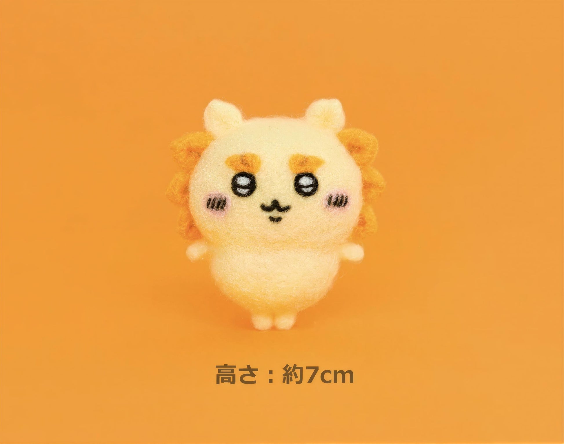 A small, cute, and colorful plush toy with a smiling expression is shown against an orange background.