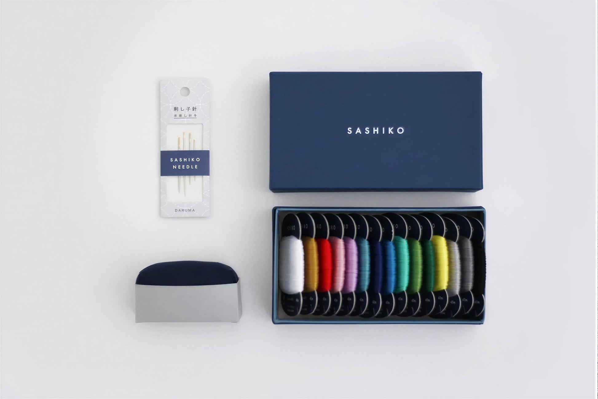 a collection of sewing-related items, including a package of sewing needles, a box of colorful thread, and a small container.