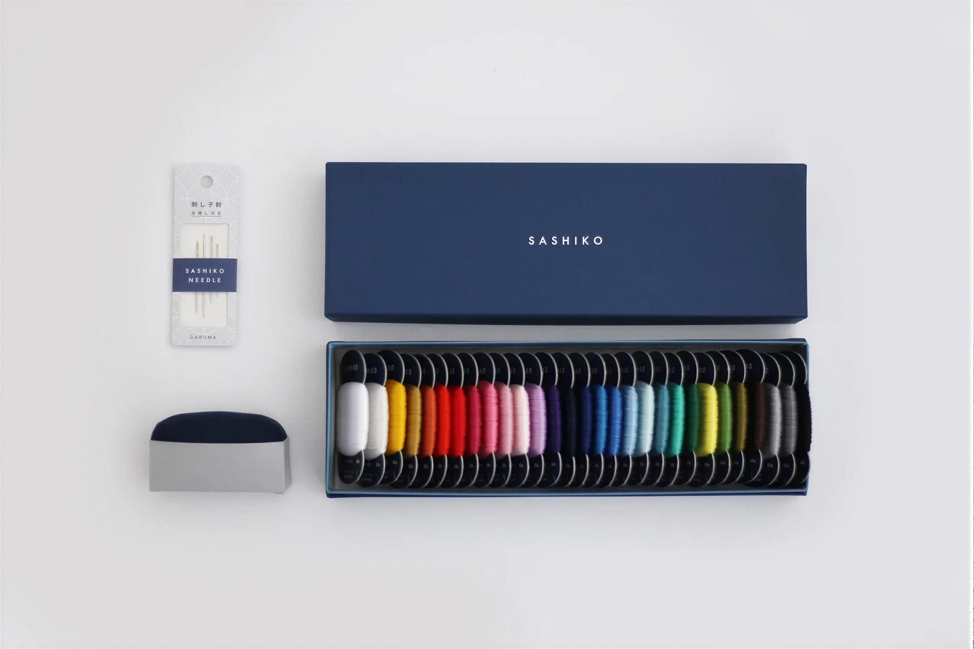 a collection of sewing supplies, including a box of colorful spools of thread, a package of thread, and a small container.