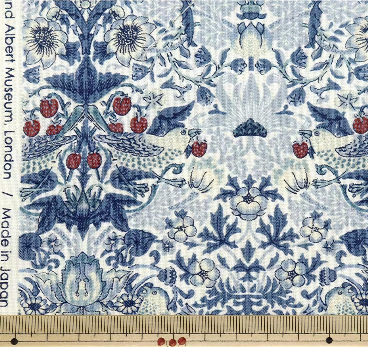 The image is a close-up of a fabric with a repeating pattern of blue and white floral designs, including flowers, leaves, and birds. The pattern is intricate and detailed, showcasing the craftsmanship of the fabric.