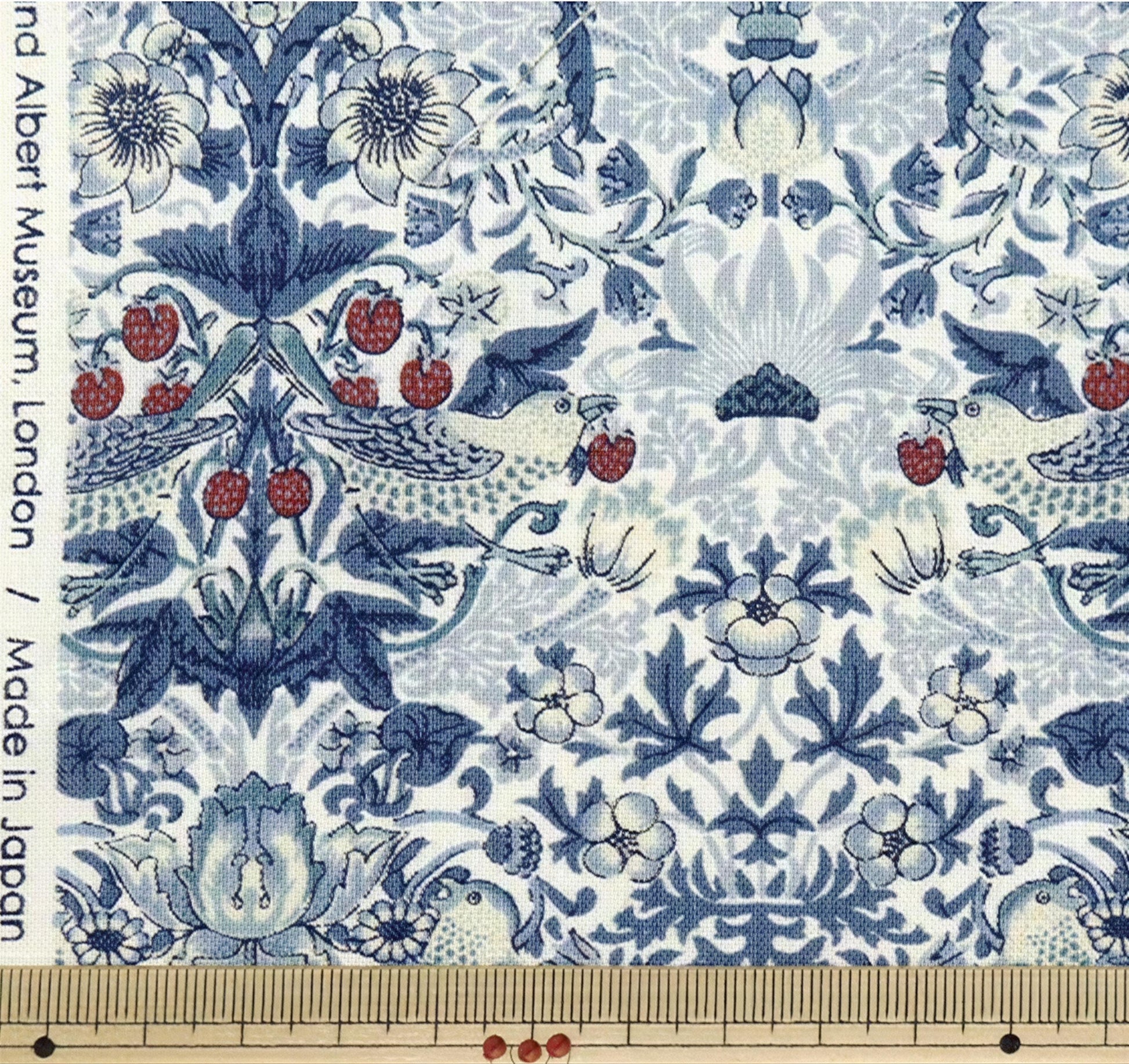The image is a close-up of a fabric with a repeating pattern of blue and white floral designs, including flowers, leaves, and birds. The pattern is intricate and detailed, showcasing the craftsmanship of the fabric.