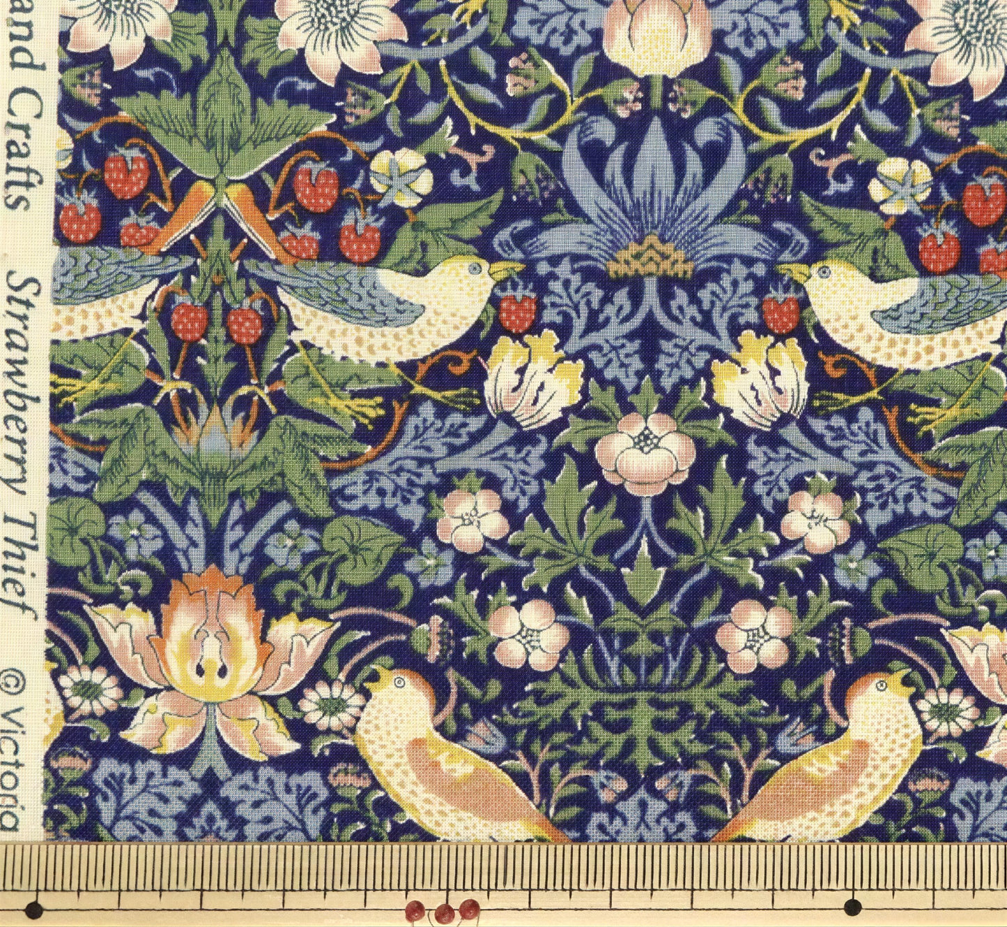 The image is a close-up of a fabric with a detailed floral and bird motif. The fabric features a variety of flowers, leaves, and birds in different colors and sizes, creating a vibrant and intricate pattern. The fabric appears to be a hand-woven textile, showcasing the craftsmanship and artistry involved in its creation.