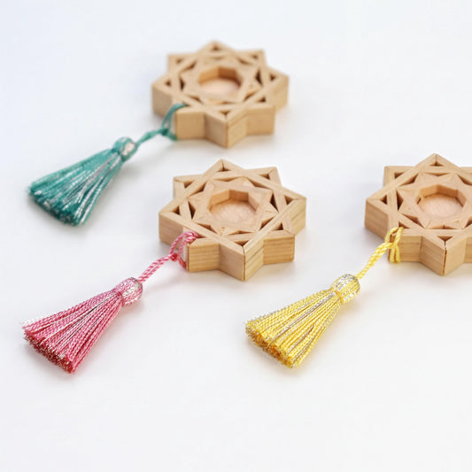 three wooden star-shaped objects with tassels attached to them, arranged on a white background.