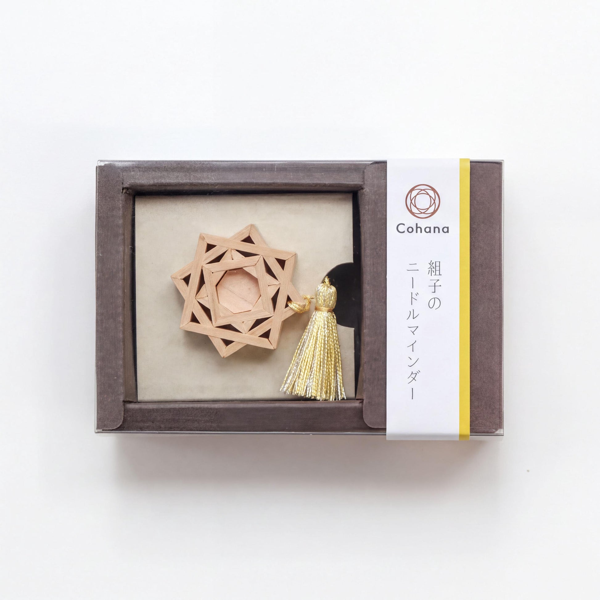 A wooden star-shaped ornament with a tassel, displayed in a brown box with Japanese text.