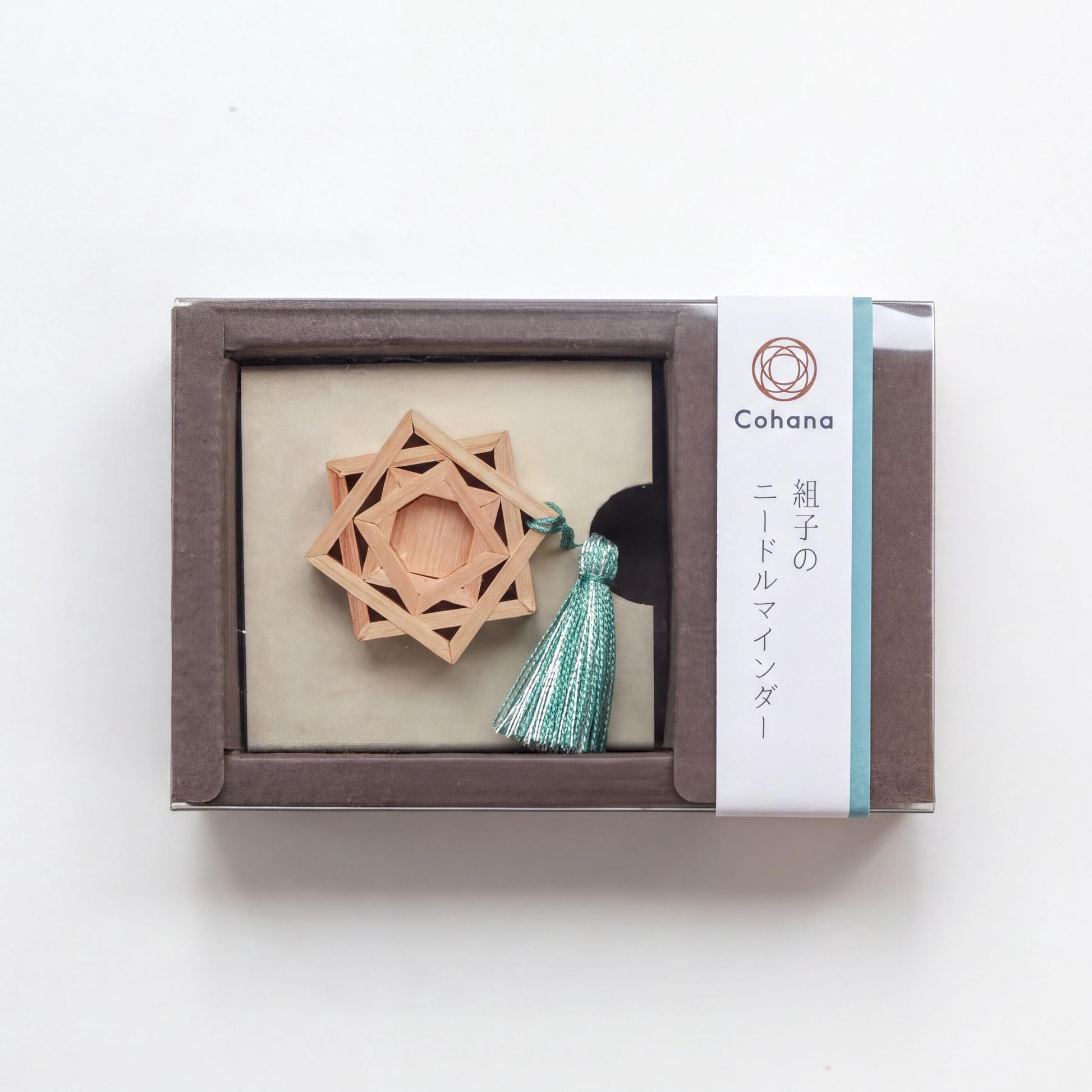 A wooden star-shaped ornament with a tassel, displayed in a brown box with a label that includes Japanese text.