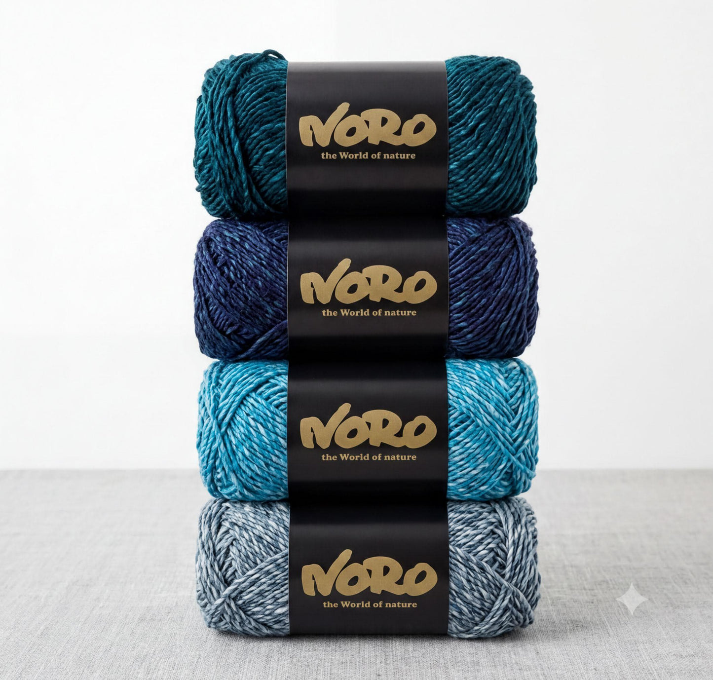 a stack of four balls of yarn, each with a black label that displays the text "NERO the World of nature".