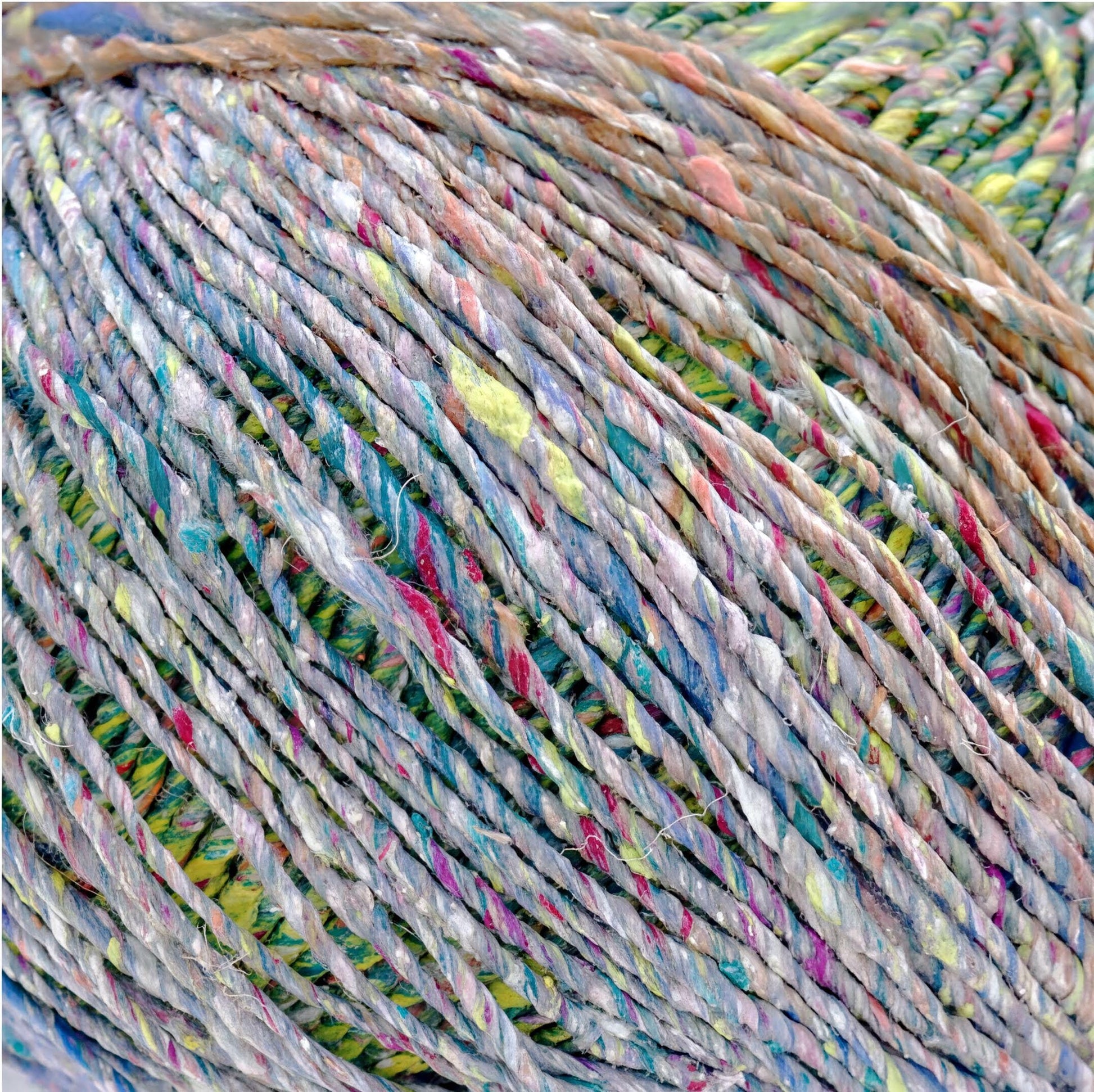 a close-up view of a ball of multicolored yarn, with the yarn's strands twisted and intertwined in a spiral pattern.