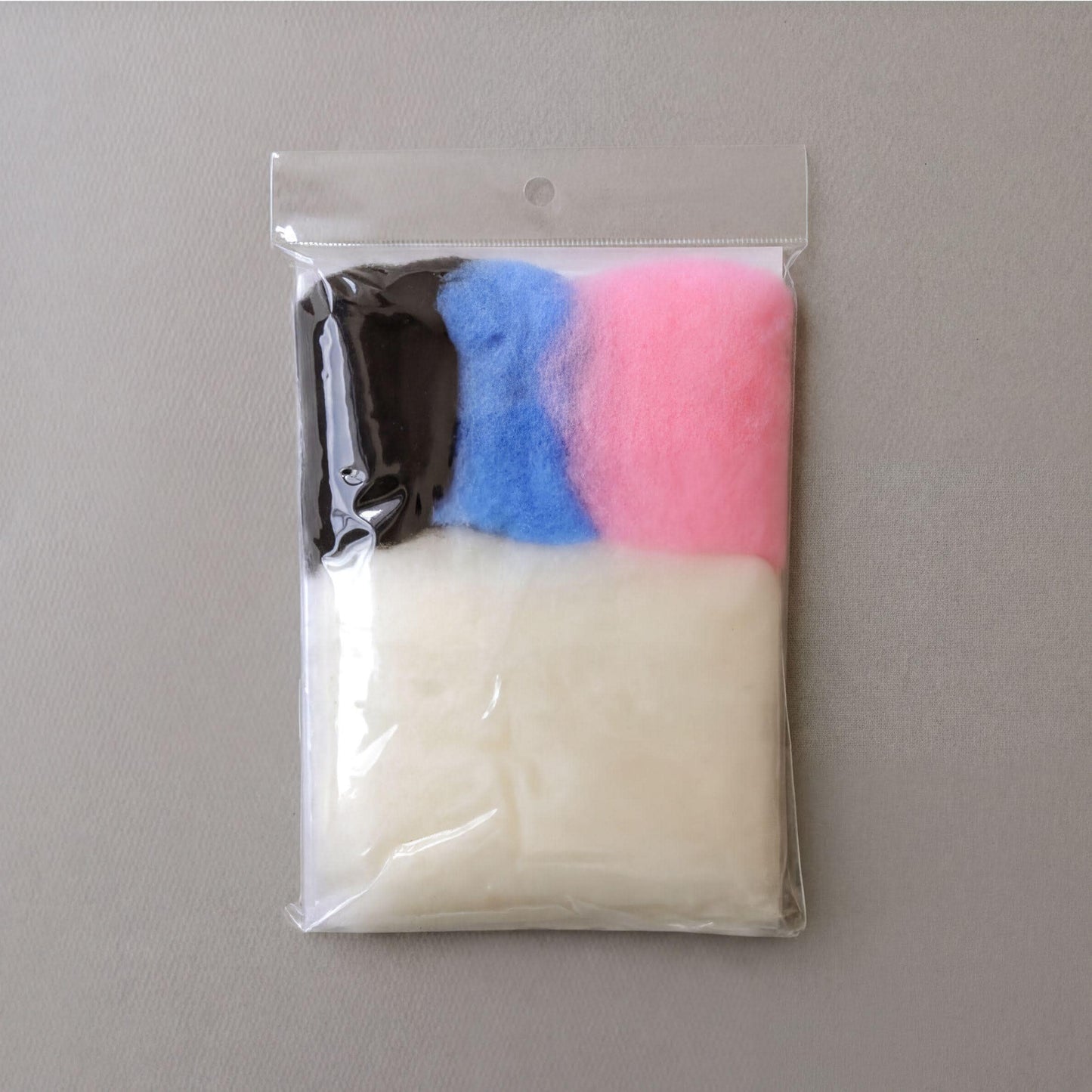 A clear plastic bag containing three different colored balls, including white, black, and pink.