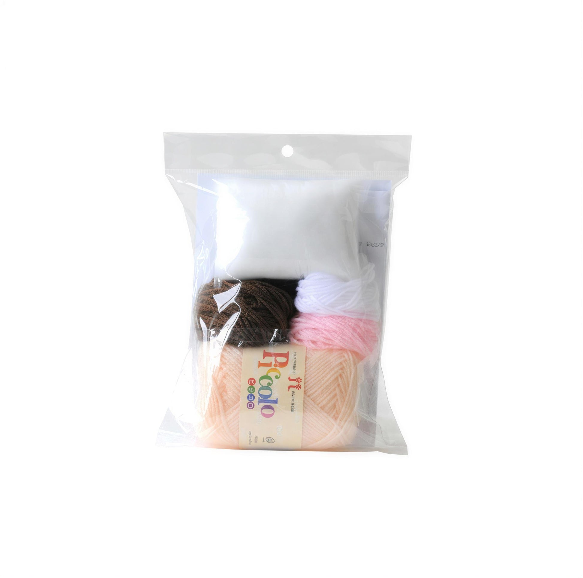A clear plastic bag containing various yarn colors, including white, brown, and pink, along with a label that reads "Ricolo".