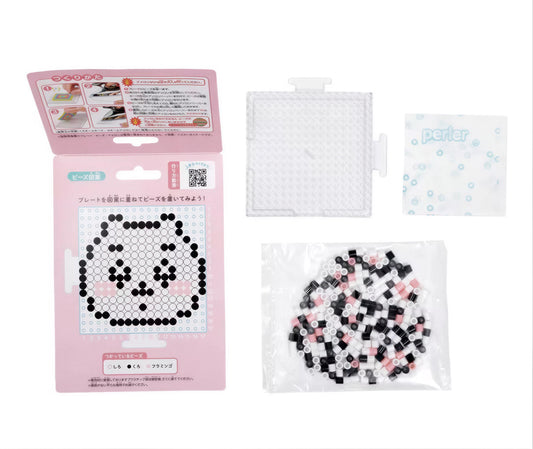 a pink box with instructions for creating a pixel art design, a clear plastic bag filled with small black and white beads, and a small white square with instructions.