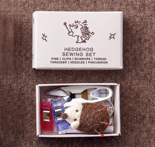 A sewing kit box with a hedgehog design on the lid, containing various sewing tools and accessories.