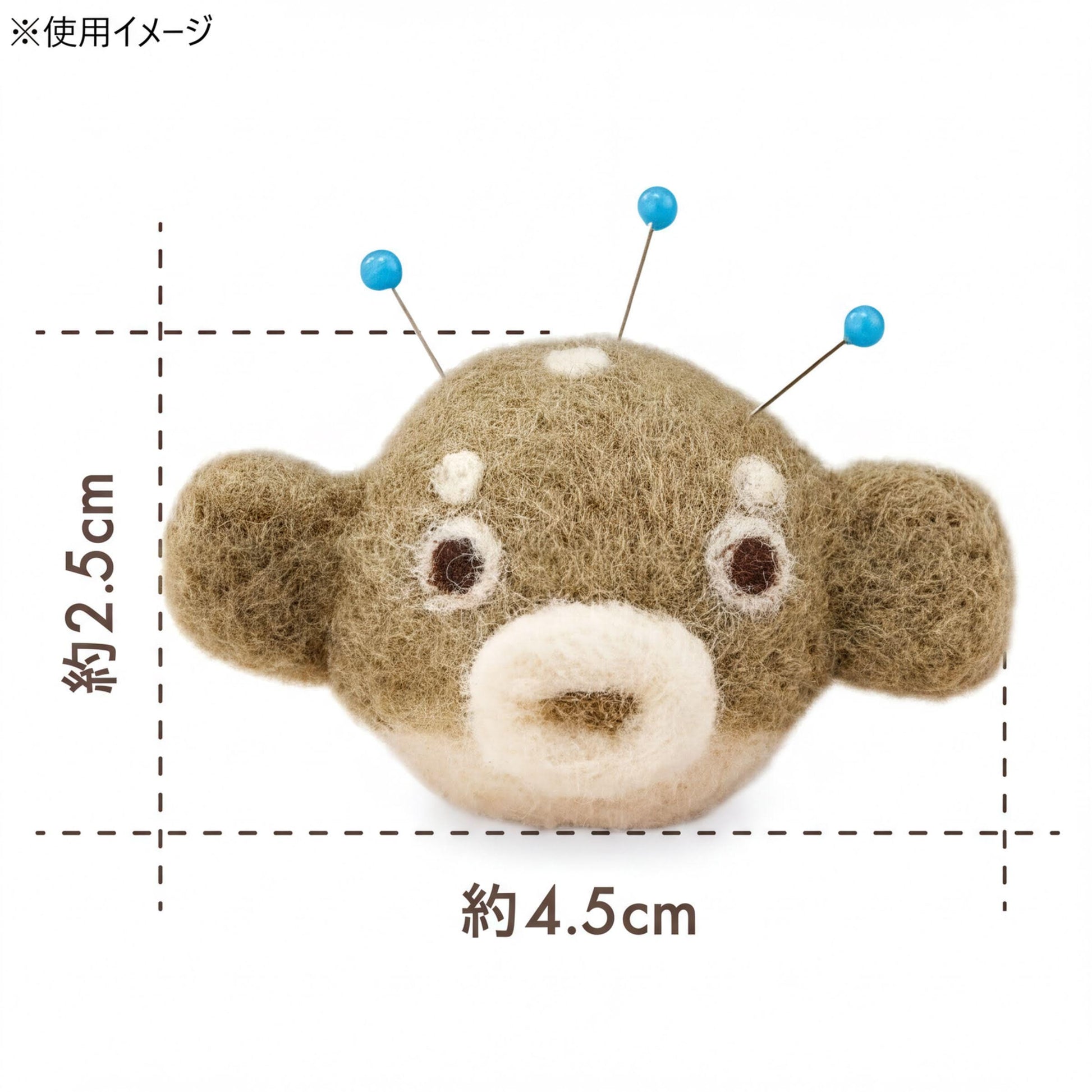 A stuffed animal needlepoint head with blue pins protruding from its ears, along with measurements indicating it is 4.5 cm in size.