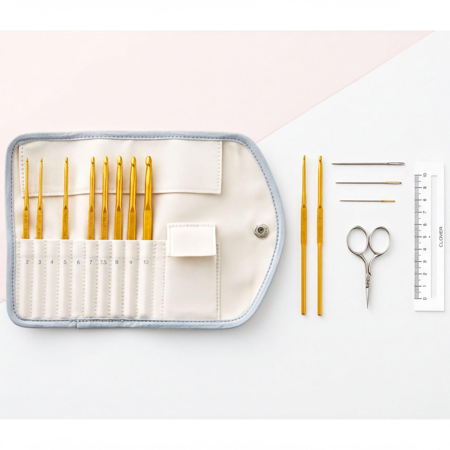 A crochet set consisting of a white case with a zipper, a ruler, a pair of scissors, and a pair of crochet hooks is arranged on a white background.