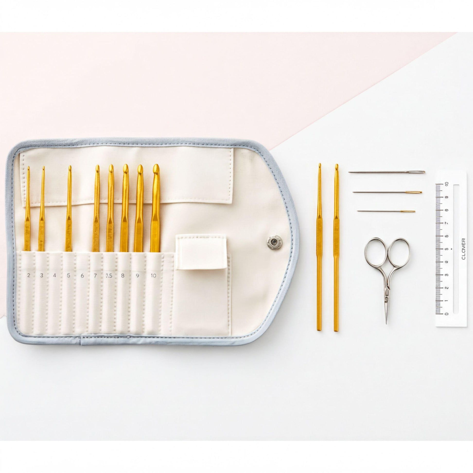 A crochet set consisting of a white case with a zipper, a ruler, a pair of scissors, and a pair of crochet hooks is arranged on a white background.
