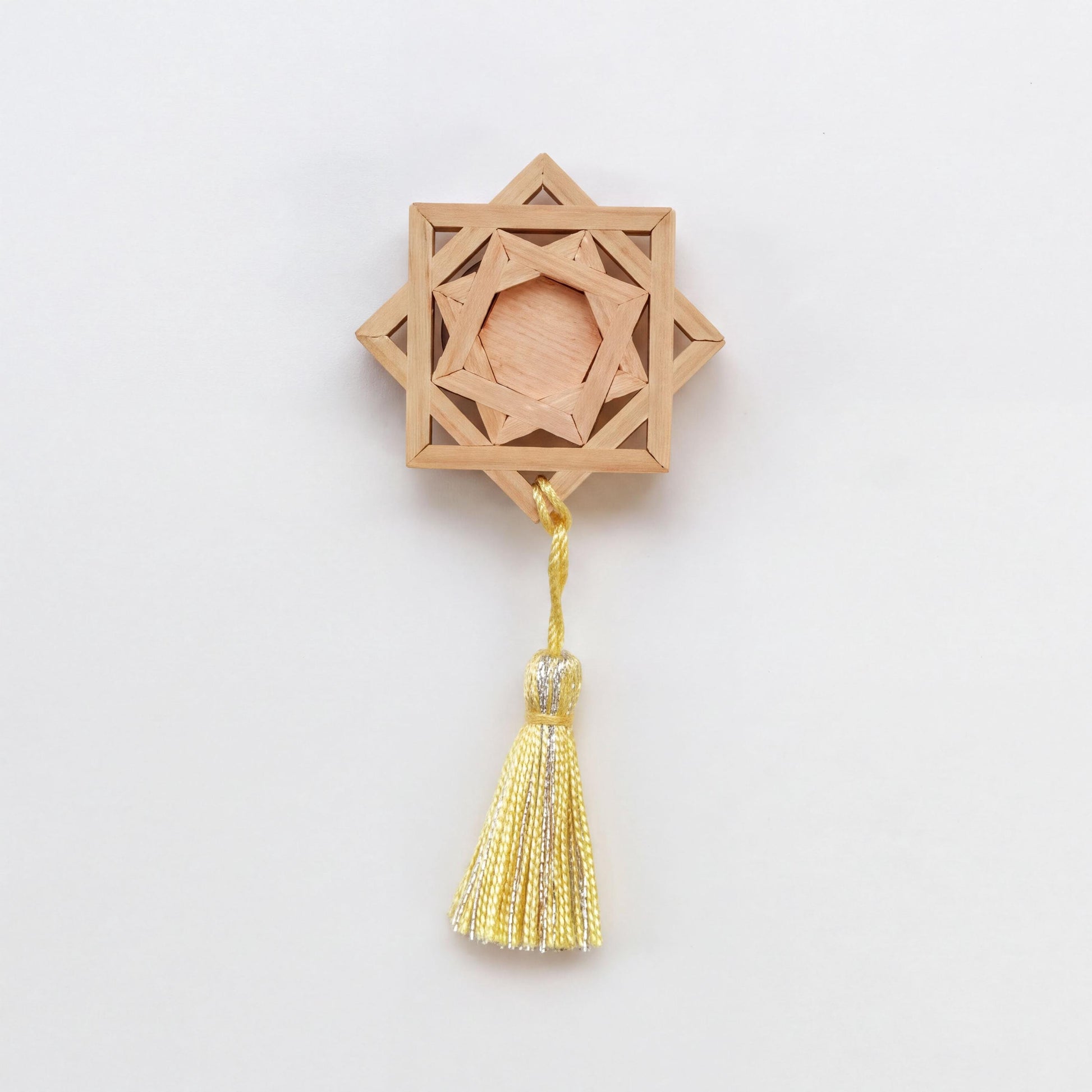 A wooden star-shaped ornament with a tassel hanging from it.