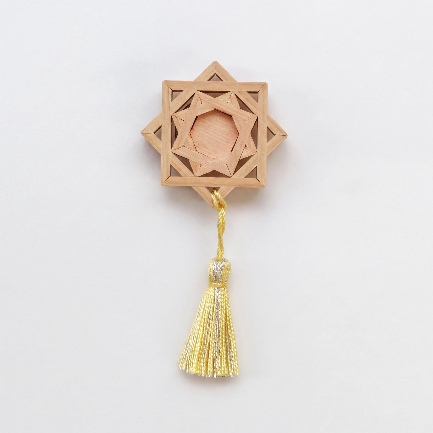 A wooden star-shaped ornament with a tassel hanging from it.