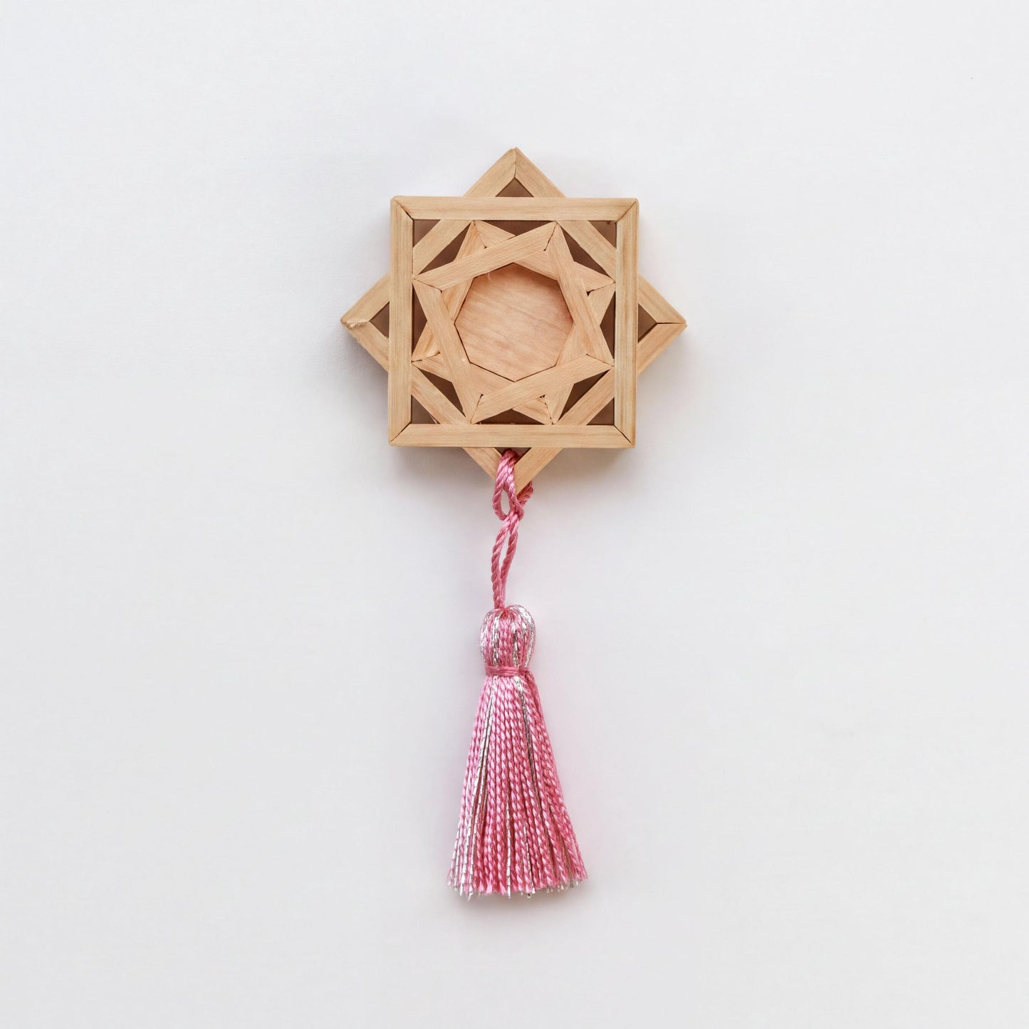 A wooden star-shaped ornament with a tassel hanging from it.