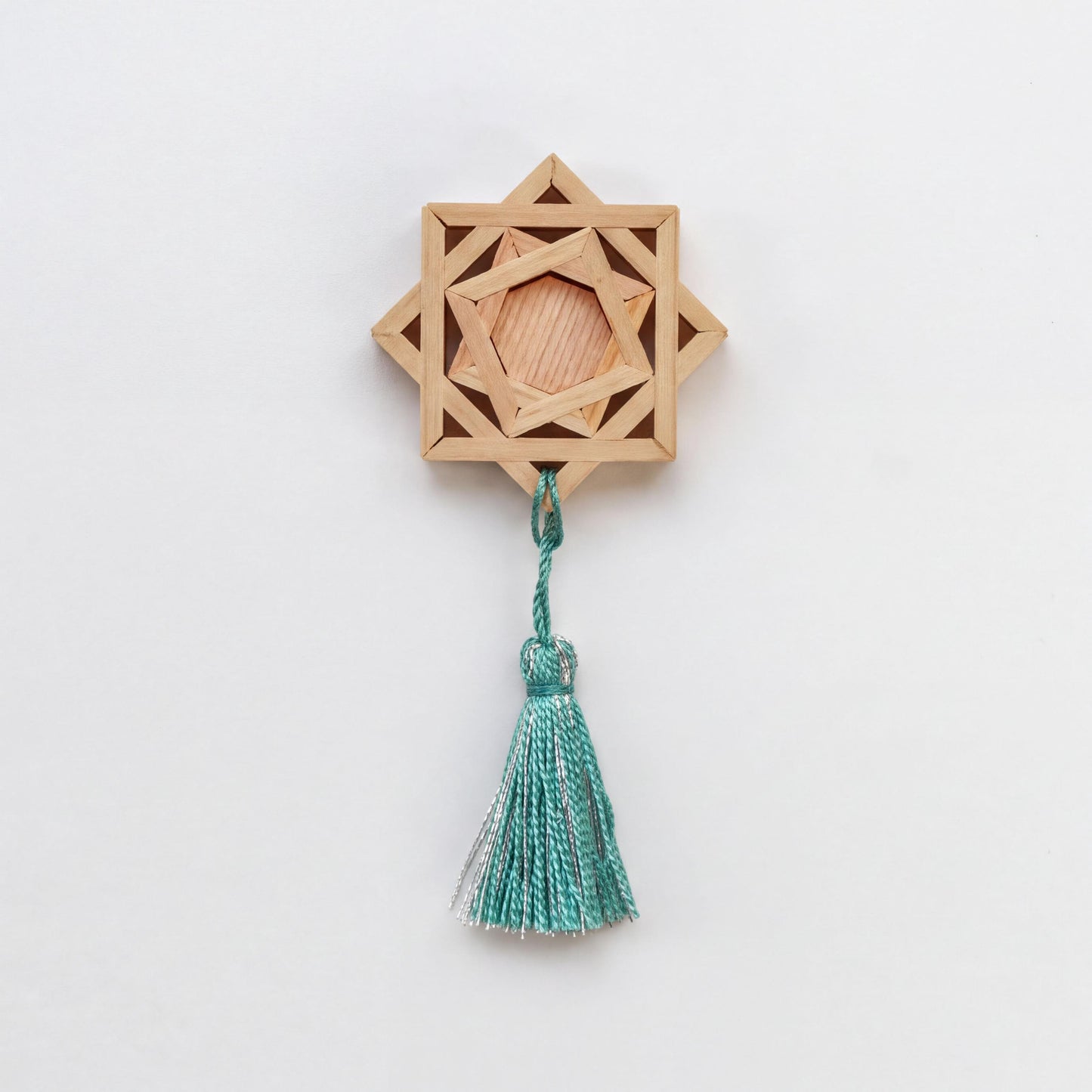 A wooden star-shaped ornament with a tassel hanging from it.