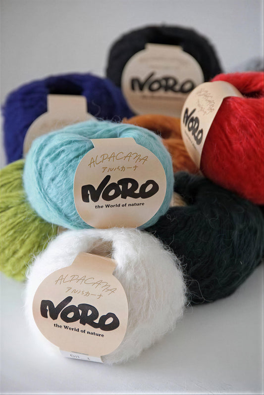 a collection of yarn balls in various colors, including blue, green, red, and white, with labels that read "ALPHA-CAPAña Twister®" and "the World of nature".