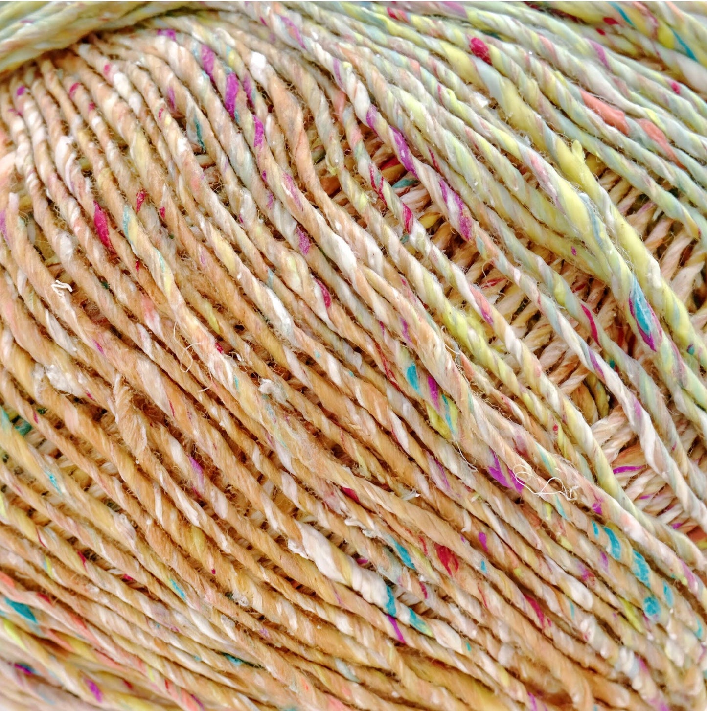 A close-up image of a ball of multicolored yarn, with the yarn's strands twisted and interwoven in a crisscross pattern.