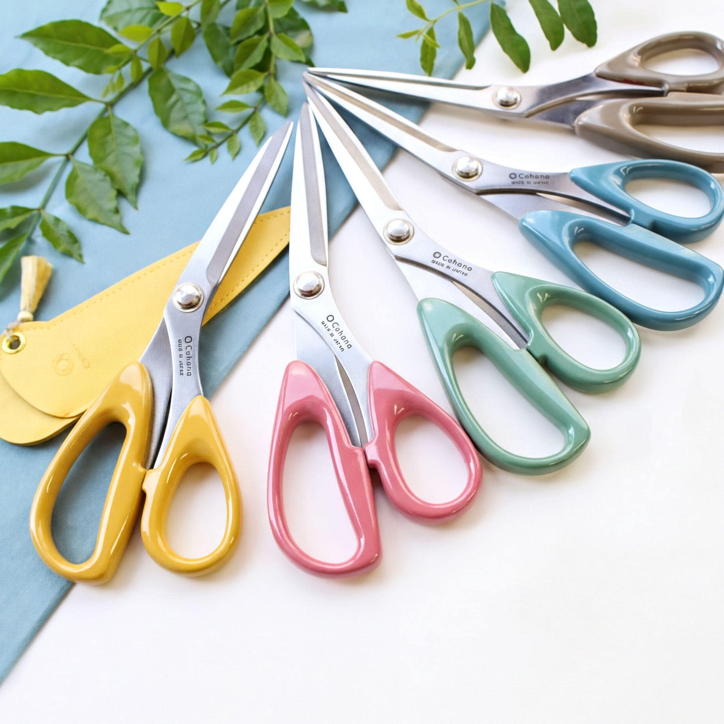 A collection of colorful scissors with various designs and colors, including yellow, pink, blue, and green, arranged on a white surface.