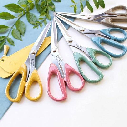 A collection of colorful scissors with various designs and colors, including yellow, pink, blue, and green, arranged on a white surface.