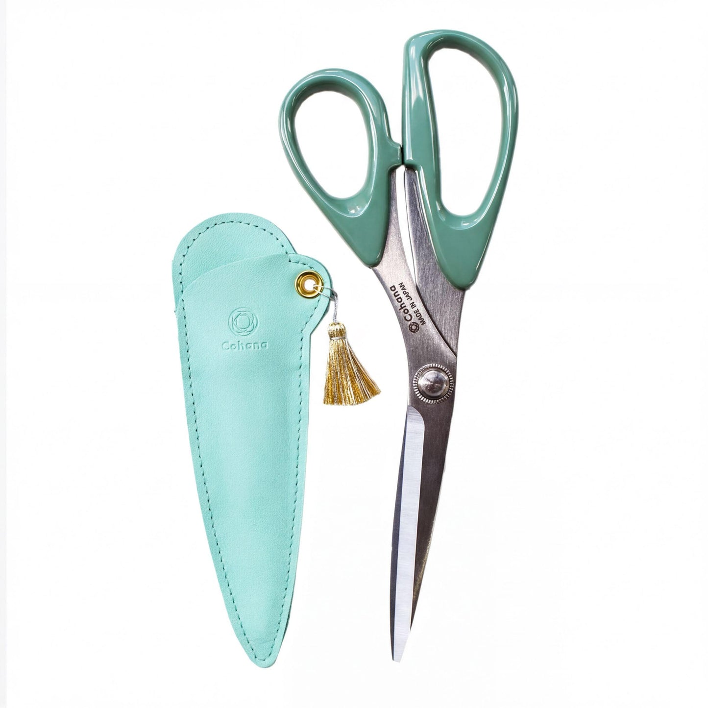 A pair of green-handled scissors with a tassel hanging from the handle, placed next to a matching green leather case.